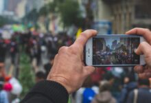 selective focus photography of person taking photo of crowd during daytime